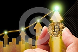 Bitcoin or cryptocurrency prices rise up positive, golden coin holding in a hand with up arrow chart