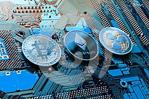 Bitcoin, Ethereum, Ripple coins on computer motherboard, cryptocurrency investing concept