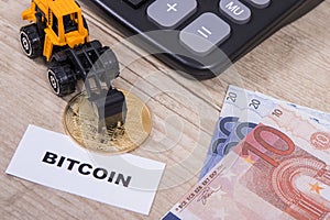 Bitcoin, euro bills, miniature excavator and calculator. Cryptocurrency. International network payment. Finance concept