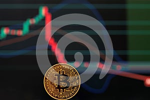 Bitcoin gold coin and defocused downward graph in dark