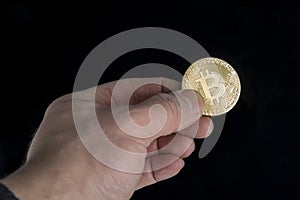 Bitcoin gold coin in hand on dark background