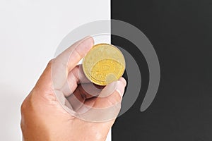 Bitcoin halving concept in cryptocurrency. Human hand holding coin in black and white background.