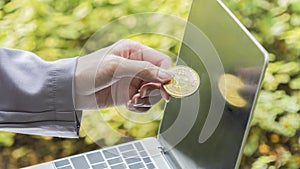 Bitcoin in hand pull off the black screen laptop. Crypto currency sign. Future concept financial currency.