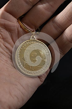 Bitcoin keychain in man hand on black background