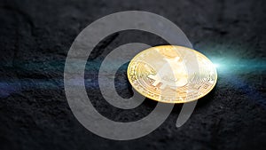 Bitcoin logo on flat black stone with light flare. cyber cryptocurrency money concept