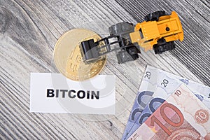 Bitcoin, miniature excavator and euro. Cryptocurrency. International network payment. Finance concept