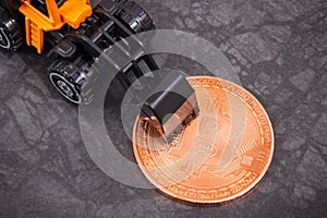 Bitcoin and miniature excavator, symbol of electronic virtual money and mining cryptocurrency