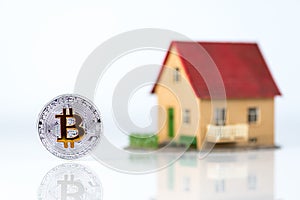 Bitcoin and private house model at light background. Real estate theme. Concept of Buying a property for crypto currency