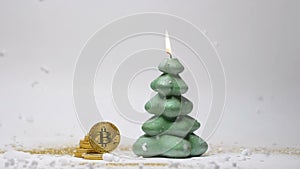 Bitcoin on Rib by Green Christmas Tree Candle Closeup