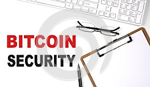 BITCOIN SECURITY text written on the white background with keyboard, paper sheet and pen