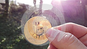 Bitcoin shining with the sun in contre jour. Hand holding bitcoin
