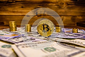 Bitcoin, stacks of the coins and one hundred dollar bills on wooden table