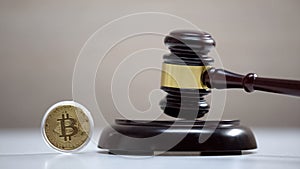 Bitcoin on table, gavel standing on sound block, crypto currency legalization