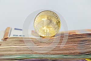 Bitcoin token on white background, on top of many euro banknotes money