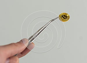 bitcoin and tweezers in the hand.