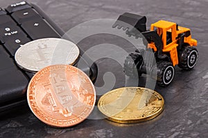 Bitcoins as symbol of electronic virtual money, miniature excavator and computer keyboard, mining cryptocurrency concept