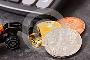 Bitcoins, calculator and miniature excavator, symbol of virtual money and cryptocurrency