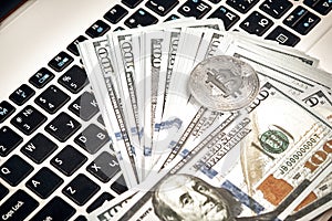 Bitcoins with dollar bills on laptop keyboard.