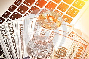 Bitcoins with dollar bills on laptop keyboard. Sun flare