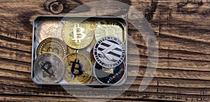 Bitcoins, litecoin and ethereum lies in metal box on old wooden background