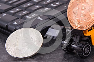 Bitcoins, miniature excavator and computer keyboard. Cryptocurrency and international network payment. Finance concept