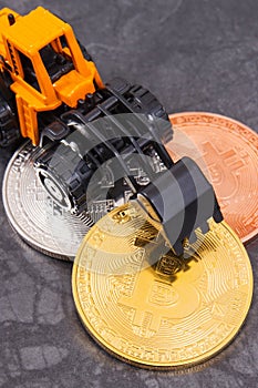 Bitcoins and miniature excavator, symbol of new virtual money and mining cryptocurrency