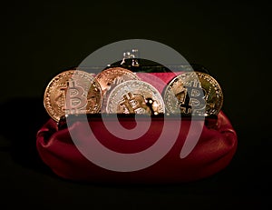 Bitcoins in red leather wallet on black