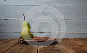 A bite pear on a plate on wooden background