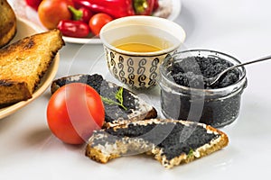 Biten fried bread, black caviar, cup of tea and vegetable.