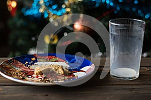 Bitten biscuit, crumbs and a empty glass of milk