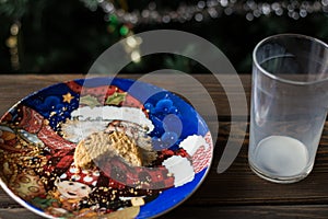 Bitten biscuit, crumbs and a empty glass of milk on a Christmas tree background