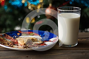 Bitten biscuit, crumbs and a glass of milk on a Christmas tree background