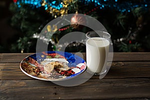 Bitten biscuit, crumbs and a glass of milk on a Christmas tree background