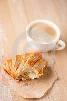 Bitten croissant and cup of cappuccino coffee