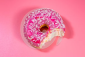 Bitten donut with glazed top isolated on a pink background