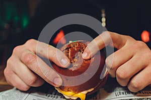 A bitten fresh burger in the hands of a man.