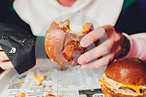 A bitten fresh burger in the hands of a man.