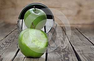 A bitten green apple is reflected with its beautiful undamaged side in the mirror. Two points of view.