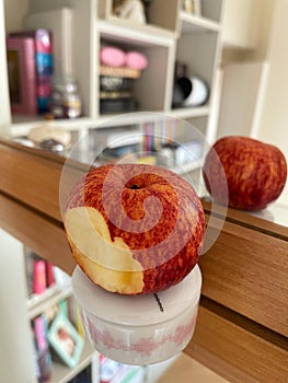 A bitten juicy apple on a white surface and reflected in the mirror