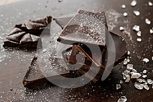 Bitter Chocolate Pieces with Sea Salt on Dark Wooden Surface.