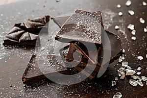 Bitter Chocolate Pieces with Sea Salt on Dark Wooden Surface. photo