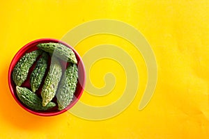 Bitter cucumber on plate on yellow background,called Karela in Hindi,Copy space, top view