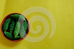 Bitter cucumber on plate on yellow background,called Karela in Hindi,Copy space, top view