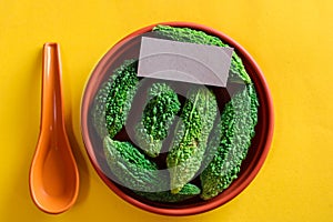 Bitter cucumber on plate on yellow background,called Karela in Hindi,Copy space, top view