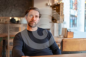 Bitter and disillusioned middle aged caucasian male sitting at the table in coffee shop