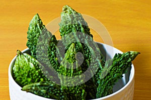 Bitter gourd green pieces closeup on isolated table background