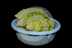 Bitter Gourds In Plastic Basket Isolated On Black