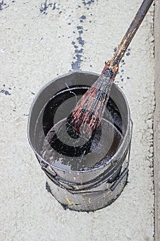 Bitumen Emulsion in metal bucket which is applied with a broom