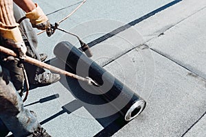 Bituminous membrane waterproofing system details and installation on flat rooftop. Professional construction worker  installing