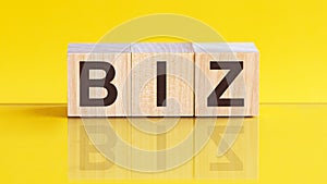 Biz word is made of wooden building blocks lying on the yellow table